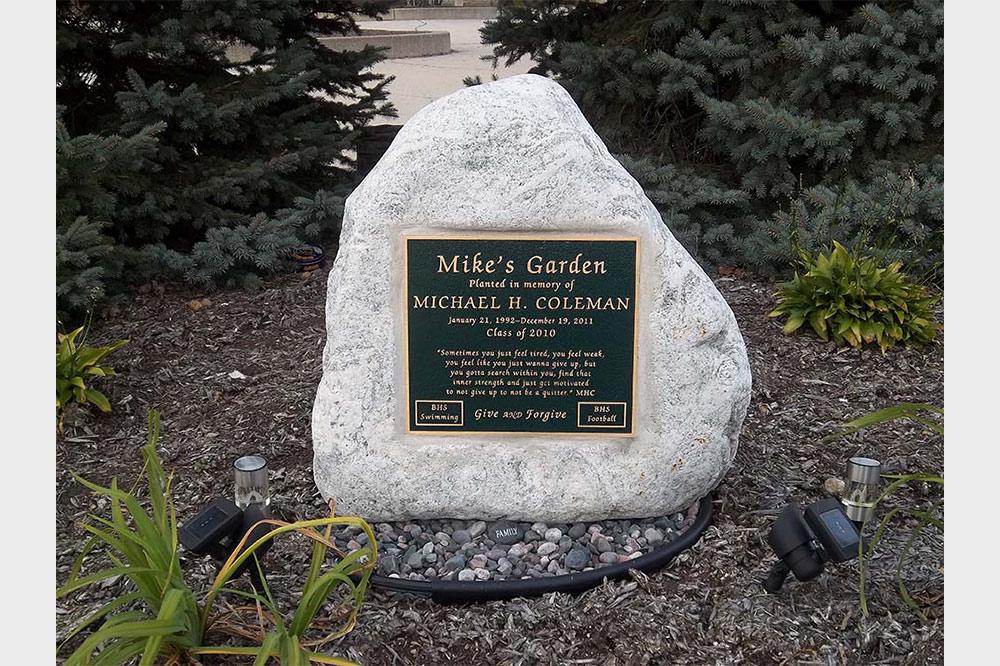 Bronze plaque recessed into white boulder in garden