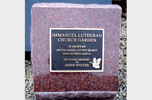 Bronze plaque with butterfly mounted on red granite pedestal