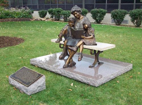 Bronze statue of woman reading to children
