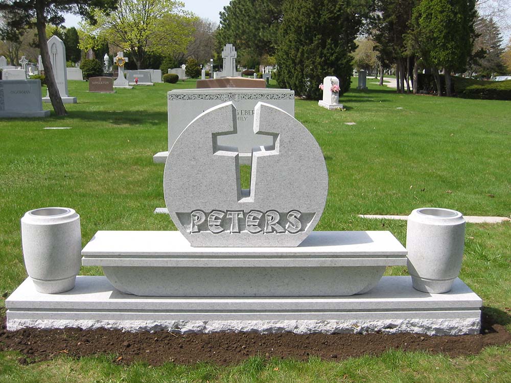 Grey granite bench monument with cross, vases, and custom lettering