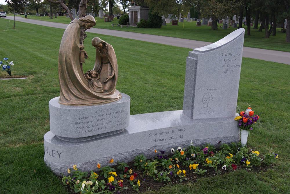 Family monument in grey granite with bronze sculpture of the Holy Family